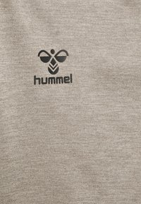 Logo d'abeille stylisé noir avec le texte « hummel » en dessous sur un fond en tissu texturé gris clair.