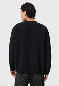 Μαύρο φούτερ από απαλό ύφασμα, με στρογγυλή λαιμόκοψη, μακριά μανίκια και ριμπ τελείωμα. Απλός σχεδιασμός χωρίς ορατά σχέδια ή λεπτομέρειες.