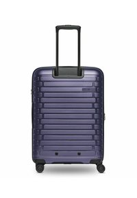 Valigia rigida di colore viola scuro con righe orizzontali testurizzate, manico retrattile nero e quattro ruote girevoli per la mobilità.