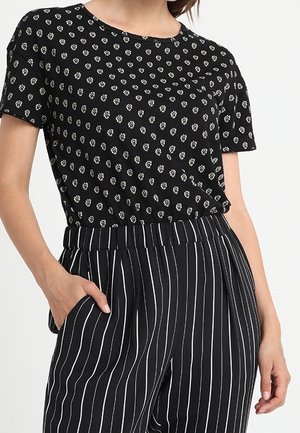 Top corto nero a maniche corte con motivo floreale bianco; abbinato a pantaloni a righe verticali bianche e nere; vita elastica e tasche laterali.
