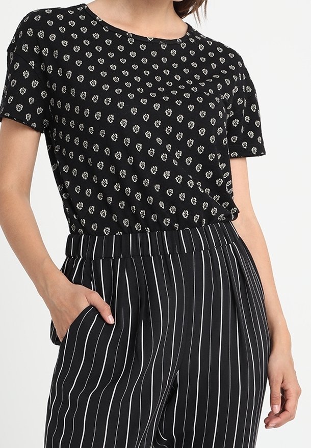 Top negro de manga corta con patrón de flores blancas; combinado con pantalones de rayas verticales en negro y blanco; cintura elástica y bolsillos laterales.