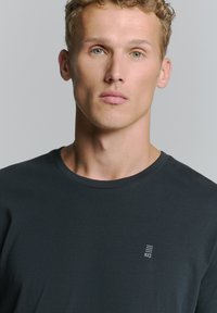 Zwarte t-shirt met korte mouwen, een ronde hals en een klein logo op de linkerborst. Gemaakt van zachte, ademende stof.