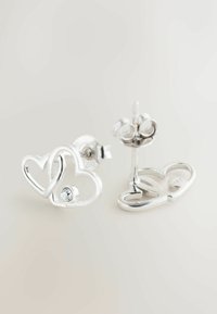 Strieborné náušnice v tvare srdca s hladkým povrchom. Jedna náušnica obsahuje malý vsadený drahokam. Dizajn s puzetou a motýlikovým zapínaním.