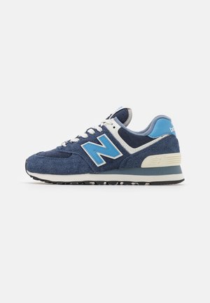 Baskets New Balance bleu marine et bleu clair avec lacets et semelle blanches, vues de côté sur fond blanc uni.