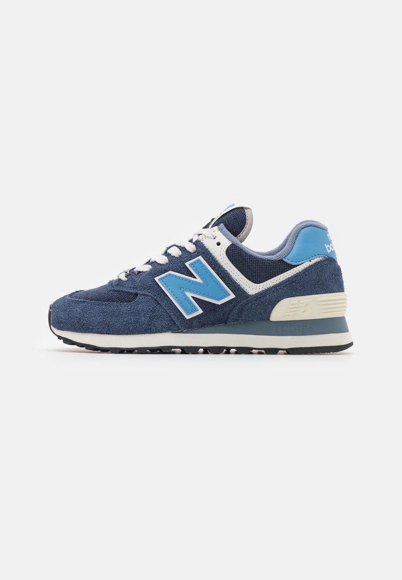 Baskets New Balance bleu marine et bleu clair avec lacets et semelle blanches, vues de côté sur fond blanc uni.