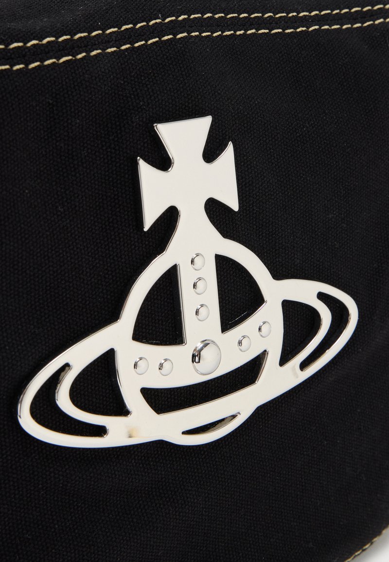 Glinsende sølvkugle med kors og ringdetalje, fastgjort til sort stof med beige syning.