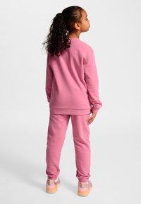 Rosa Sweatshirt und passende Jogginghose aus weicher Baumwolle; die Hose hat elastische Bündchen, während das Oberteil einen Rundhalsausschnitt und eine lockere Passform aufweist.