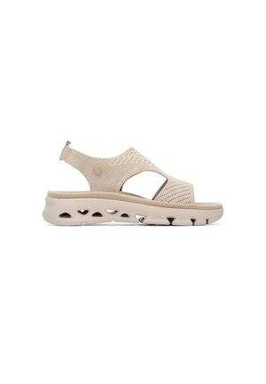 Sandalia beige de punta abierta con parte superior de tejido, tira trasera y suela gruesa con detalles recortados para ventilación y comodidad.