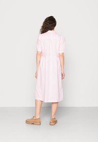 Jasnoróżowa, krótkozasięgowa sukienka zapinana na guziki z dopasowanym talią i swobodnym dołem. Materiał z mieszanki bawełny o casualowym kroju.