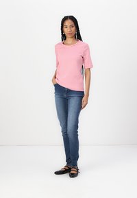Red and white striped short-sleeve shirt paired with blue jeans and black flat shoes. The shirt has a round neckline; jeans are fitted.