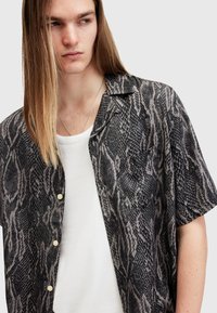 Kortærmet skjorte med et sort og grått slangeprintmønster, lavet af letvægtsstof, med krave og knapper.