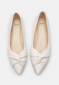 Flats en cuir blanc avec un bout pointu, présentant un design noué à l'avant. L'intérieur affiche le logo "Bata Cuir Véritable". Texture lisse.