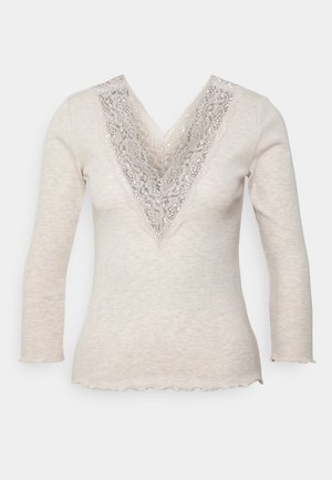 Haut en maille beige à manches longues avec un col en V profond, orné d'une large dentelle florale et d'un ourlet et de poignets légèrement froncés.