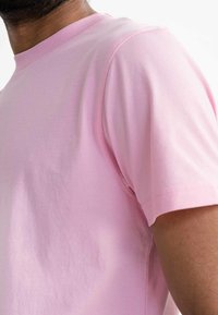 Lichtroze katoenen t-shirt met een ronde halslijn en korte mouwen, gekenmerkt door een gladde textuur en subtiele stikdetails.