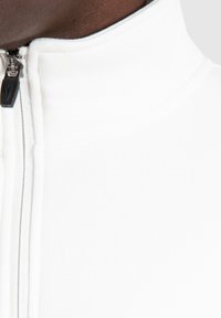 Maglione zip-up bianco con collo alto, caratterizzato da una texture liscia, cerniera nera a contrasto e dettagli sartoriali delicati sul colletto.