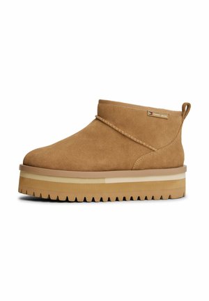 Bottines en suède marron avec un bout rond, présentant une épaisse semelle plateforme et une semelle extérieure en caoutchouc texturé. Couture décorative visible.