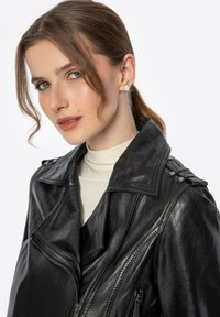 Schwarze Motorradlederjacke mit Reverskragen, durchgehendem Reißverschluss und Schulterepauletten. Glatte Textur und figurbetonter Schnitt.
