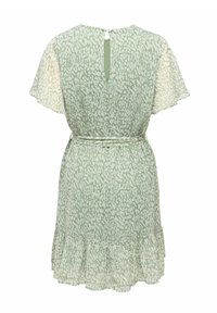 Robe courte vert clair avec motifs blancs abstraits, manches volantées, ceinture à la taille, ouverture en forme de trou de serrure dans le dos, et ourlet à volants.