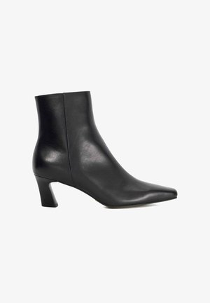 Bottines en cuir noir avec un bout pointu et un talon block. Texture lisse, design minimaliste et silhouette ajustée.