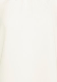 Top in tessuto bianco con una texture liscia, dotato di scollatura arricciata e un design semplice. Senza motivi visibili o decorazioni.