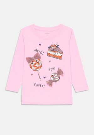 Rosa Langarm-T-Shirt mit illustrierten Süßigkeiten: einem Kuchen, einem Lutscher und Bonbons, mit dem Text "SÜSS!", "LECKER!" und "LUSTIG!" aufgedruckt.