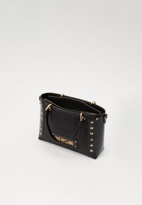 Bolsa preta com textura acolchoada, ferro dourado, detalhes com tachas e uma placa de log�ótipos. Possui duas alças e fecho com zip.