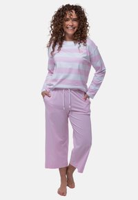 Maglietta a maniche lunghe a strisce rosa chiaro con un piccolo ricamo di faccina sorridente, abbinata a pantaloni corti rosa uniti con vita elastica.