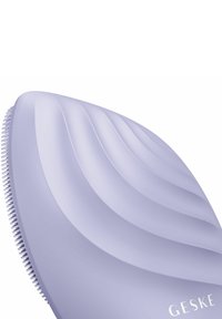 Hårborste med en böjd, ergonomisk design och vågiga räfflor. Tillverkad av mjuk lila plast med fina borst längs en kant.