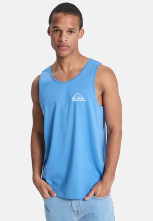 Hellblaues Baumwoll-Top mit Rundhalsausschnitt und kleinem weißem Logo auf der Brust. Kombiniert mit hellen Jeansshorts, die eine entspannte Passform zeigen.