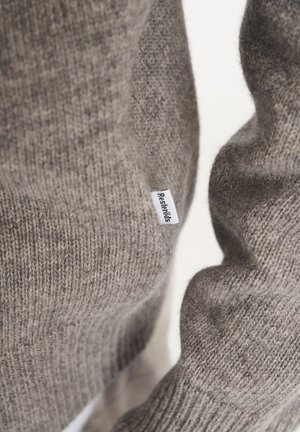 Maglione grigio realizzato in tessuto a maglia, caratterizzato da un motivo testurizzato e un piccolo tag con il marchio cucito di lato.