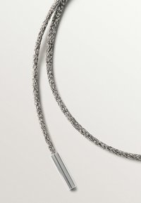 Cable de plata trenzado con un extremo metálico liso y cilíndrico. Superficie texturizada con un acabado brillante, que muestra un diseño minimalista.
