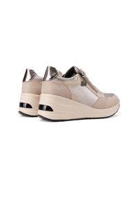 Sneakers beige con una combinazione di materiali scamosciati e lisci, caratterizzati da dettagli metallici, un tallone imbottito e una chiusura con zip laterale.