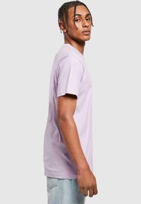 Camiseta de algodón lila con mangas cortas, cuello redondo y corte recto. Combinada con unos vaqueros de denim azul claro, con una textura suave y sin patrones.