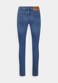 Jeans skinny de mezclilla azul mostrados desde la parte trasera, con dos bolsillos y una etiqueta de cuero marrón de la marca Diesel en la cinturilla.