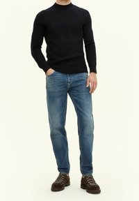 Marinblå ribbade stickade tröja med rund halsringning, långa ärmar, kombinerad med ljusblå jeans och bruna snörstövlar med texturerade sulor.