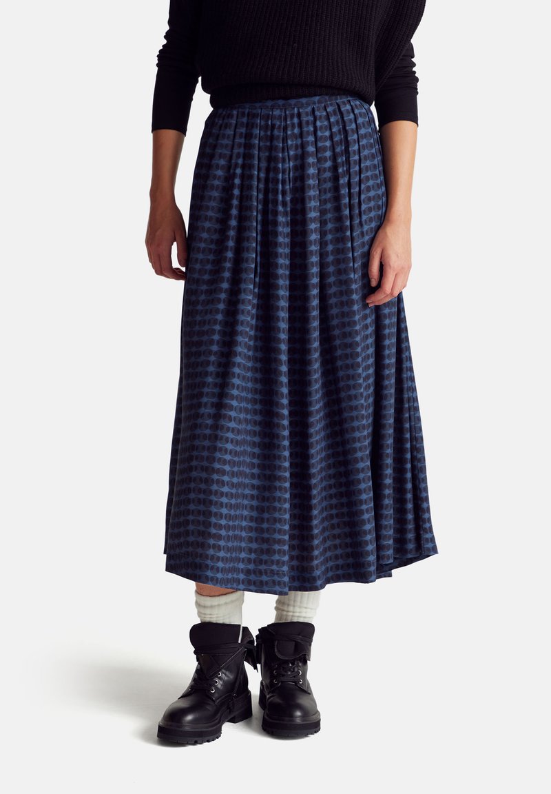 Blue pleated skirt with a circular pattern, made of smooth fabric, paired with black boots and white socks.
