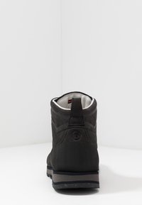 Schwarze Wildleder-Stiefelette mit strukturierten Details, gepolstertem Kragen und einer Gummisohle mit sprenkeltem Design. Die Rückansicht zeigt das Logo und Nahtakzente.