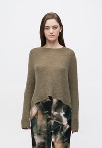 Pulover tricotat verde măsliniu cu decolteu larg, croială lejeră și stil scurtat. Are mâneci lungi și tiv ușor curbat.