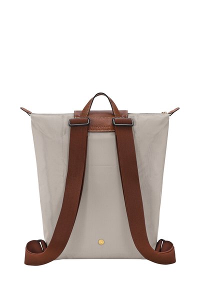 Rucksack aus hellgrauem Stoff mit dunkelbraunen Lederakzenten. Verfügt über zwei verstellbare Stoffschultergurte und einen Tragegriff oben.