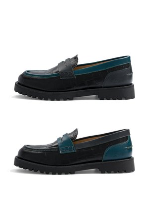 Deux mocassins en cuir noir avec un motif texturé et des accents bleu sarcelle, présentant des semelles épaisses et robustes ainsi que des détails à pampilles, vus de profil.