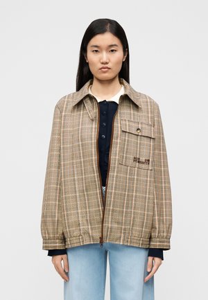 Veste beige à carreaux avec fermeture éclair et poche à bouton. Comprend un col, des poignets élastiques et un détail brodé sur la poitrine.