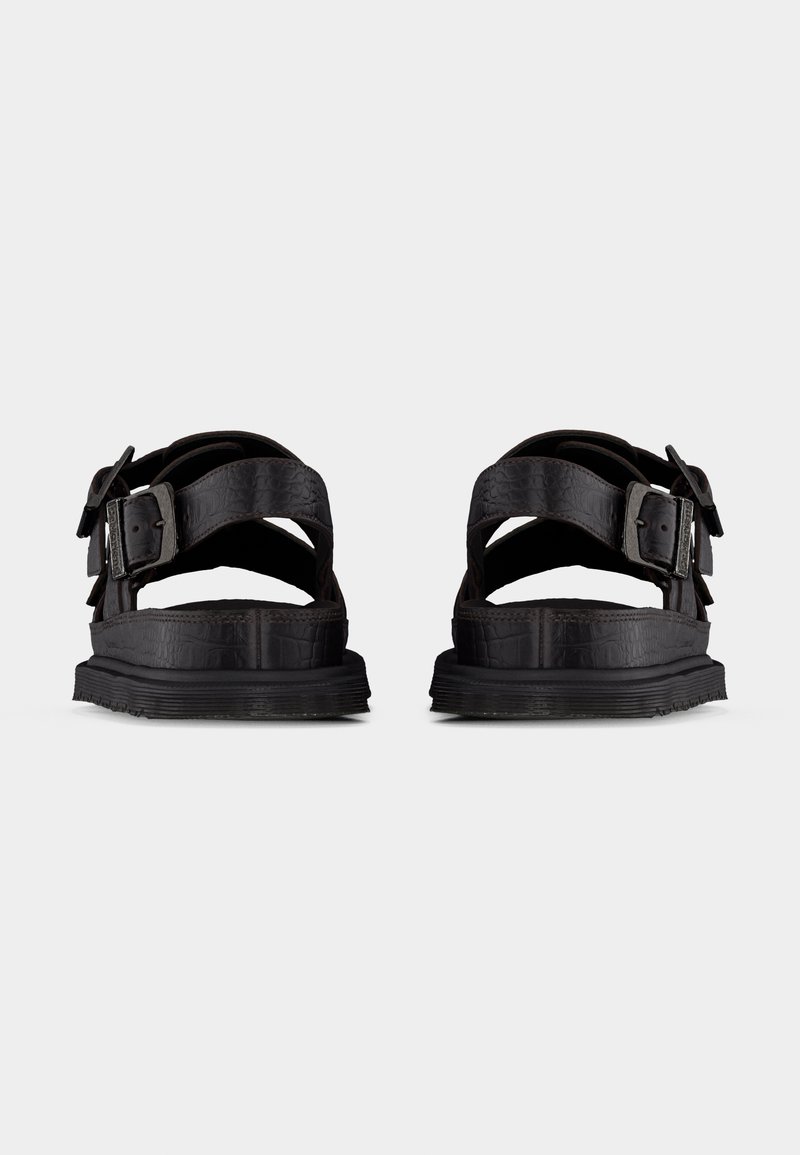 Pair of black leather sandals with thick soles and adjustable side buckles, shown from the back on a plain background.