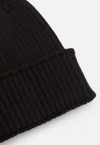 Crna pletiva kapa s mekom teksturom, s rebrastim dizajnom i preklopom za udobno prianjanje.