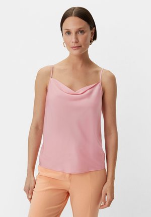 Roze cami-top met kraag en dunne bandjes, gemaakt van een zachte stof. Het heeft een zachte draping en een iets losse pasvorm, gecombineerd met lichtoranje broek.