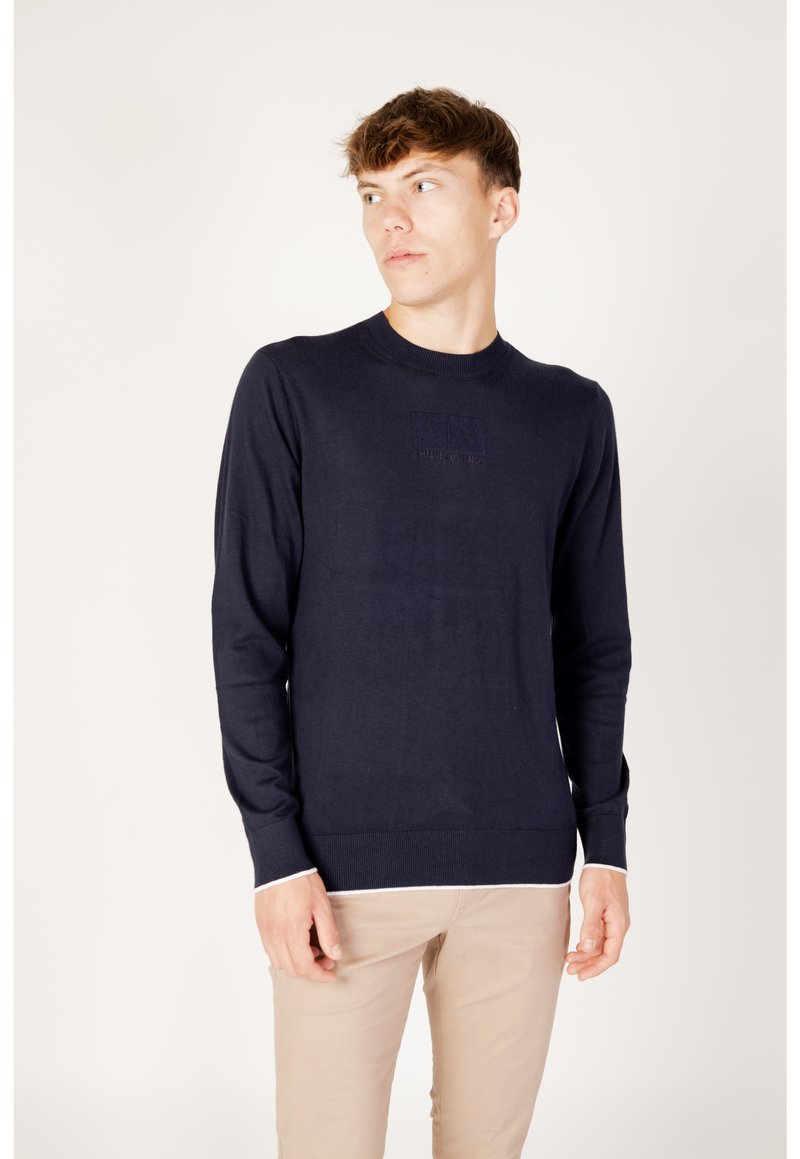 Marineblauer Strickpullover mit Rundhalsausschnitt, langen Ärmeln und weißen Akzenten an den Bündchen und am Saum. Verfügt über ein dezentes Logodetail auf der Brust.