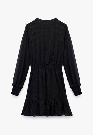 Vestido negro con mangas largas, cintura fruncida, dobladillo con volantes y tela texturada que presenta patrones sutiles a lo largo.