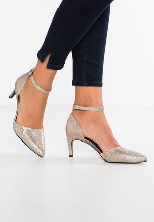 Guld, teksturerede højhælede sko med spids tå og ankelrem. Hælen er slank, og designet er åbent i siderne.