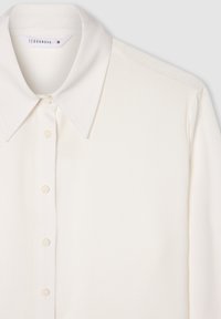 Blusa bianca a maniche lunghe con colletto classico, chiusura frontale con bottoni e texture liscia. Presenta una lucentezza sottile e nessun motivo visibile.