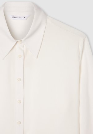 Blusa bianca a maniche lunghe con colletto classico, chiusura frontale con bottoni e texture liscia. Presenta una lucentezza sottile e nessun motivo visibile.