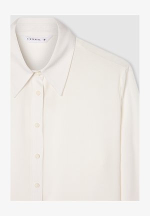 Blusa bianca a maniche lunghe con colletto classico, chiusura frontale con bottoni e texture liscia. Presenta una lucentezza sottile e nessun motivo visibile.